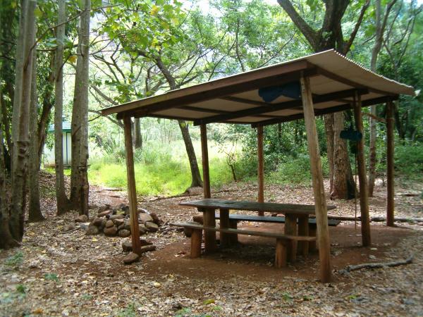 Only camp under the roof in case of a big storm, otherwise find a flat spot nearby